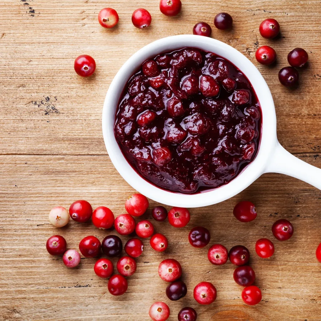 Cranberry sauce in a white ceramic container on a wood table