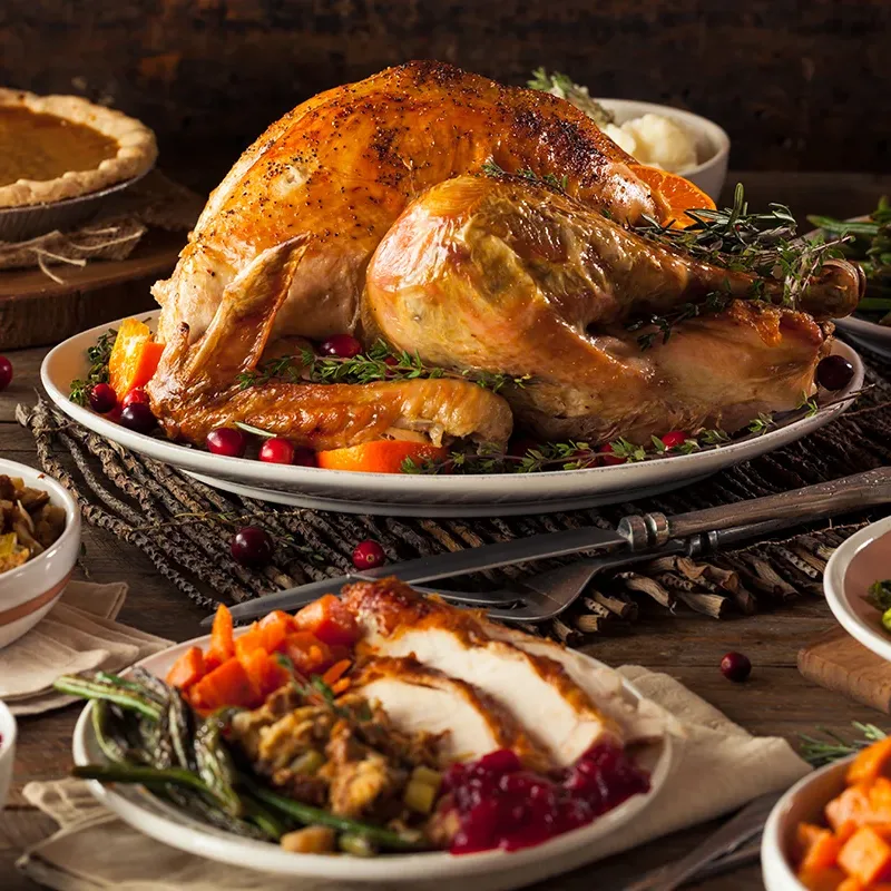 A homemade thanksgiving meal from Browns Valley Market on a dinner table, including a whole cooked turkey, pumpkin pie, cranberry sauce, and other Thanksgiving side dishes.