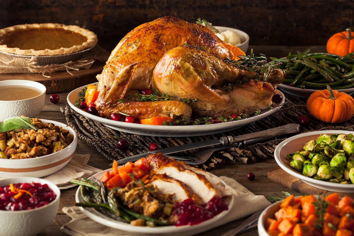 A homemade thanksgiving meal from Browns Valley Market on a dinner table, including a whole cooked turkey, pumpkin pie, cranberry sauce, and other Thanksgiving side dishes.