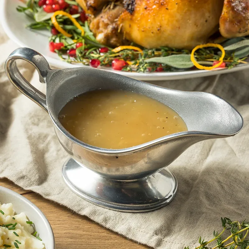 A silver boat of homemade gravy on a table of Thanksgiving dishes