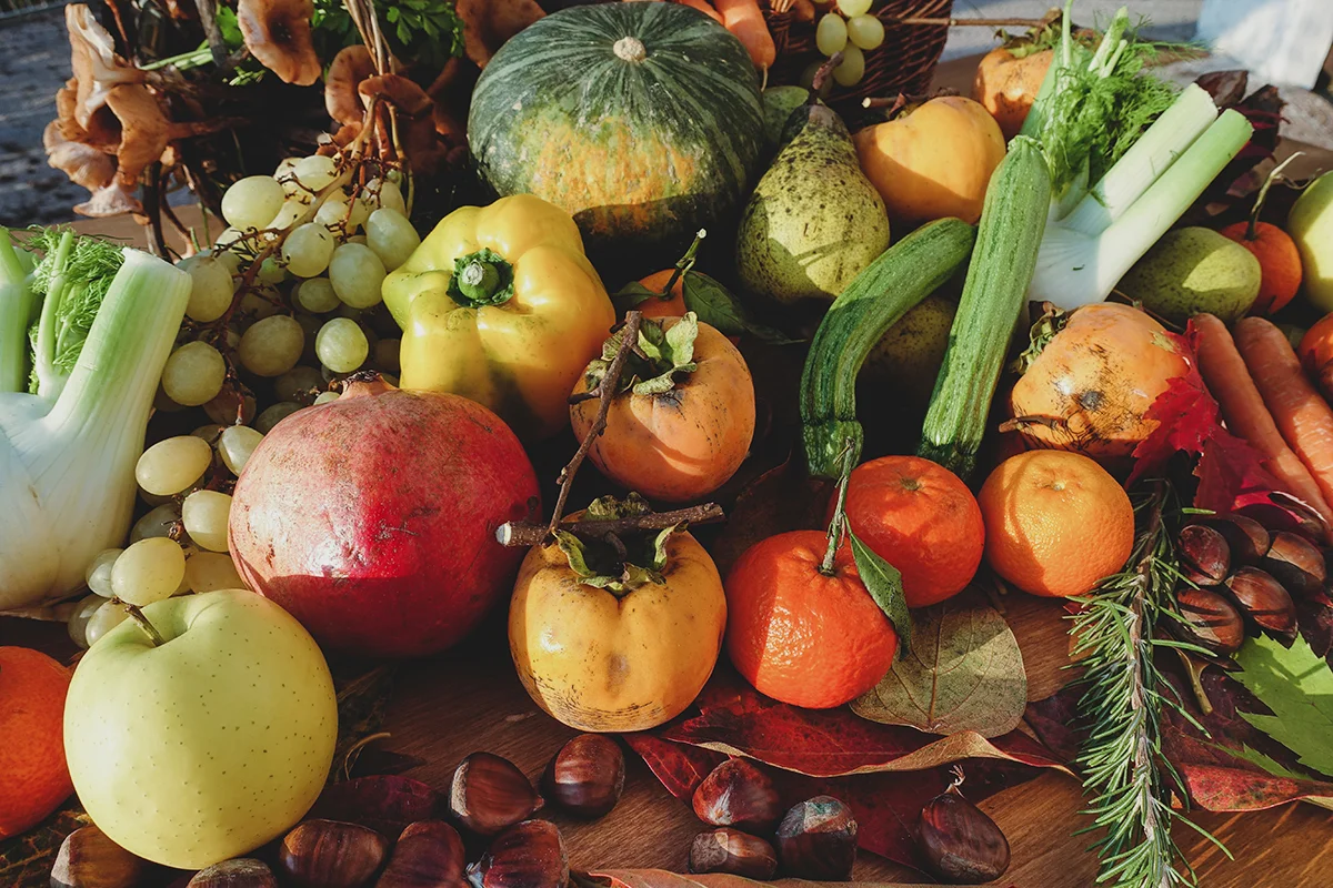 A spread of local, seasonal winter produce on a table, including citrus, squashes, pomegranates, and more, showing the concept of what's in season in Napa Supermarkets this winter