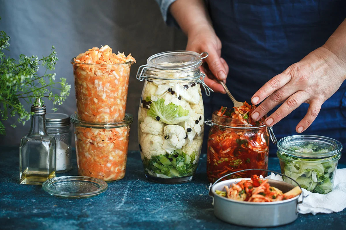 Jars of fermented foods like kimchi, sauerkraut, and fermented carrots, showing the concept of the best foods and drinks for gut health